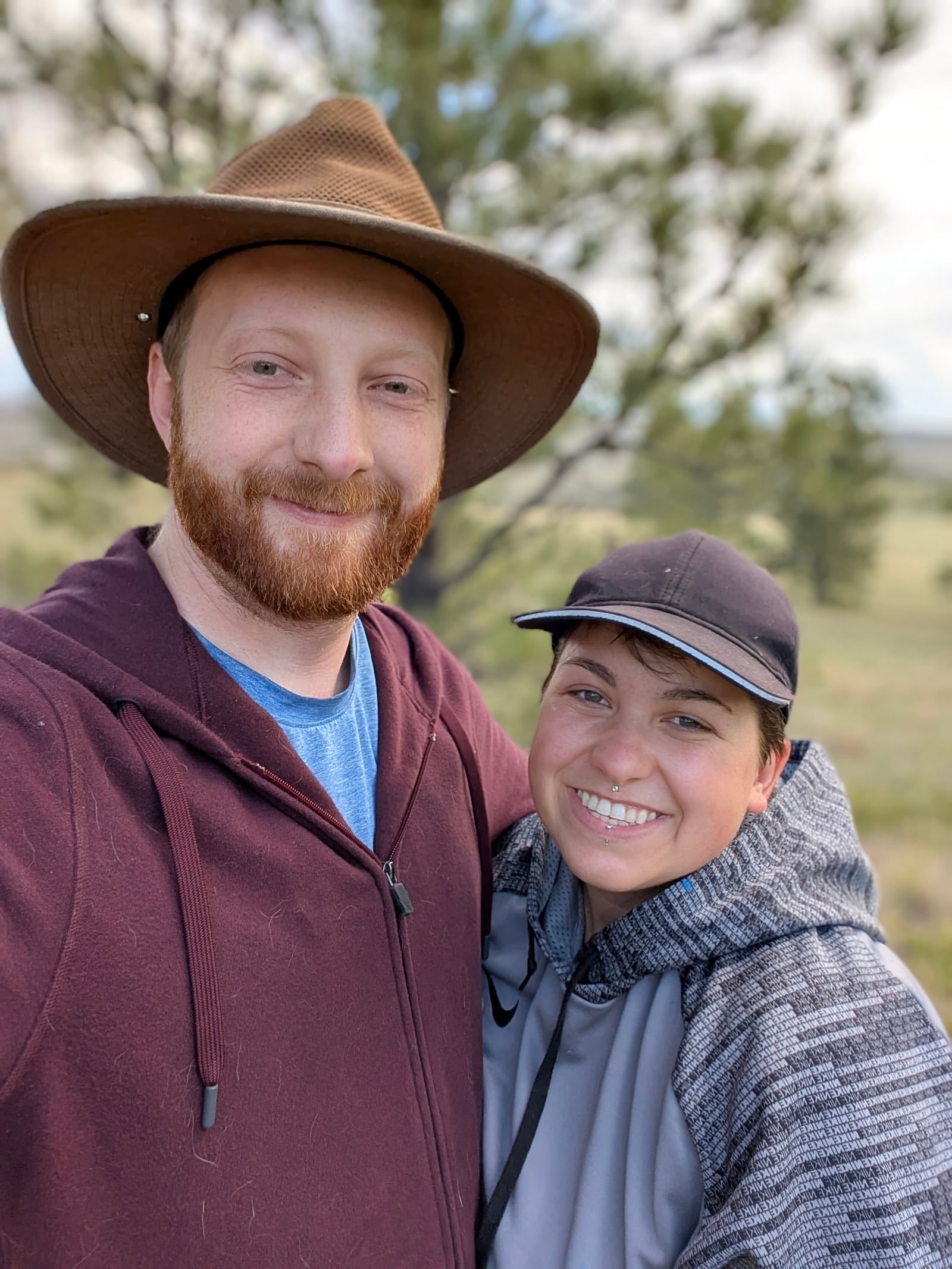 John and his wife smiling together in a Montana landscape.